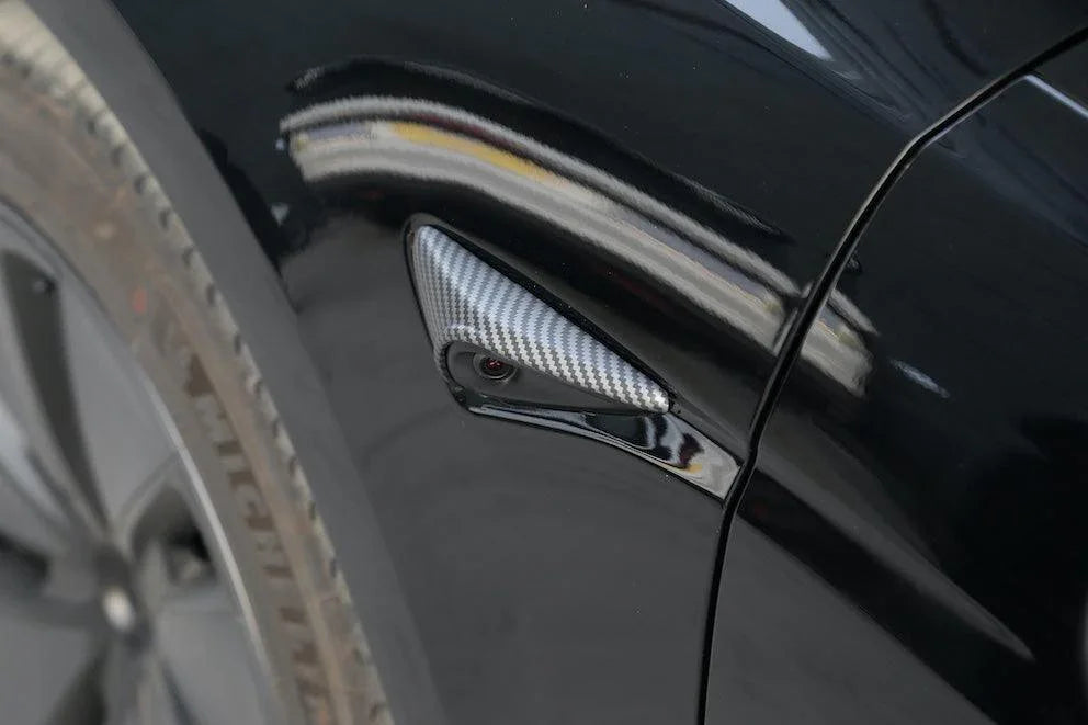 Carbon fibre side indicator camera cap installed beside the side camera on Model Y