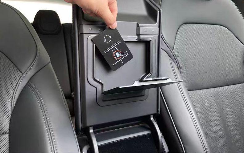 Accessing the hidden armrest storage compartment with one hand in a Tesla