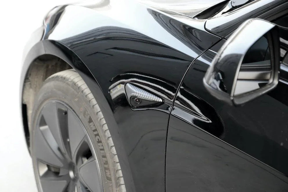 Front quarter view of carbon fibre side indicator camera caps installed on Model Y