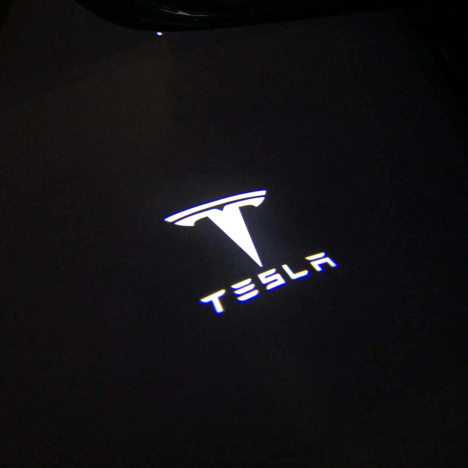 Tesla logo puddle light projection on the ground at night